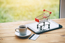 Coffee Cup And Digital Tablet With Credit Card And Trolley As Symbol Of Online Shopping And Paying
