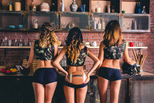 Sexy Girls From The Support Group For American Football With A Ball Standing With A Booty To The Photographer In The Kitchen. Back View. Women With The Ball Sport Football Lags Camouflage Sexual Game 