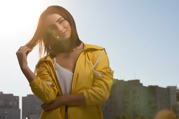 Wall Mural - Pretty woman outdoor portrait at sky background in yellow windbreaker