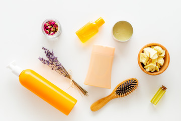 Cosmetics for hair care with jojoba, argan or coconut oil. Bottles and pieces of oil on white background top view