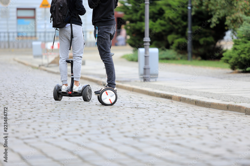 Młodzi ludzie na deskorolkach elektrycznych jadą ulicami miasta Wrocław, hoverboard. - obrazy, fototapety, plakaty 