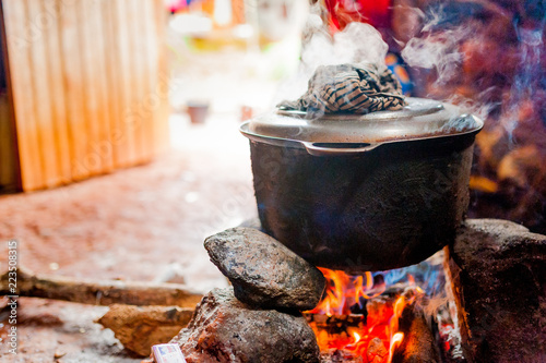 Fotografie, Obraz smoking iron pot above fire in traditional african kitchen in cameroon during co