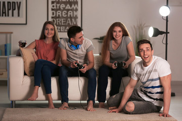 Wall Mural - Young people playing video games at home in evening