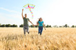 © Pixel-Shot - Happy young couple flying kite in a field
