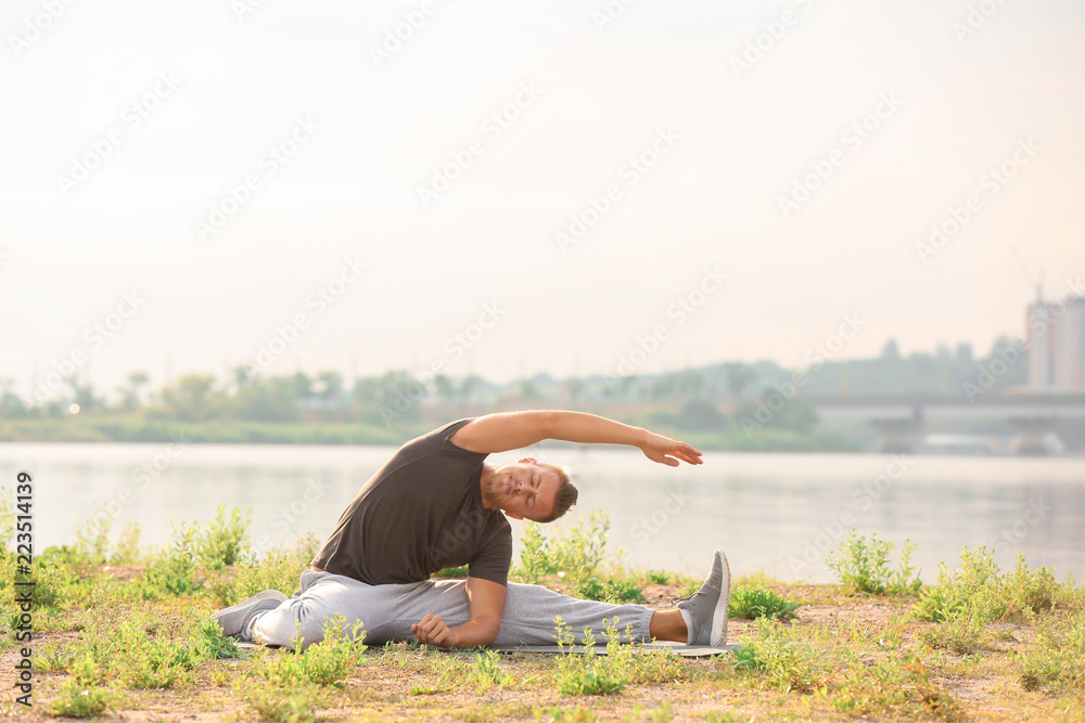 Sporty young man training outdoors near river