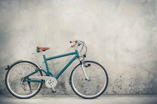 Retro bicycle with aged brown leather saddle from circa 90s front concrete wall background. Vintage old style filtered photo