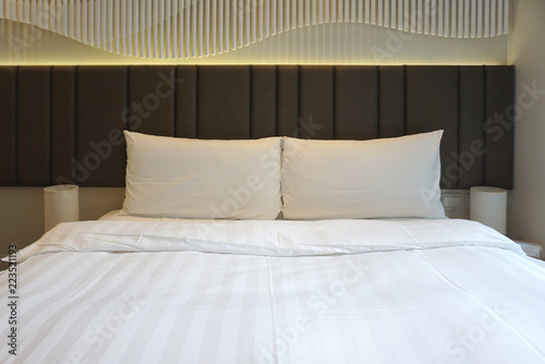 Double White Comfortable Pillows On The White Bed Sheet With Brown
