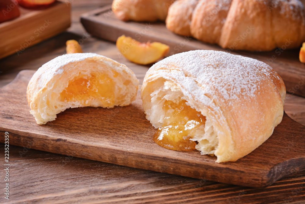 Tasty croissants with jam on wooden board