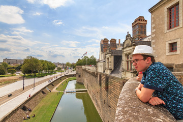 Tourist looks at the beautiful summer cityscape of Nantes, France, from The Château des ducs de Bretagne (Castle of the Dukes of Brittany)
