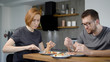 © kustvideo - Husband and wife eat breakfast together. Behind the wooden bar, behind the modern kitchen interior.