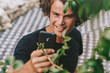 © iuricazac - Closeup shot of smiling man standing outdoors have conversation on mobile phone. Young male with curly hair resting outside in the street using wirless on his cell phone on concrete gray background