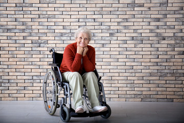 Poster - Senior woman in wheelchair against brick wall