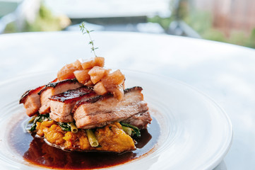 Braised pork belly in brown sauce with vegetables, modern Chinese cuisine in fine dining restaurant.