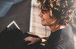 © iuricazac - Closeup rear view shot of smiling male with curly hair using laptop for chatting online with friends and earphones to listening the music, connected to free wireless. Handsome man texting messages.