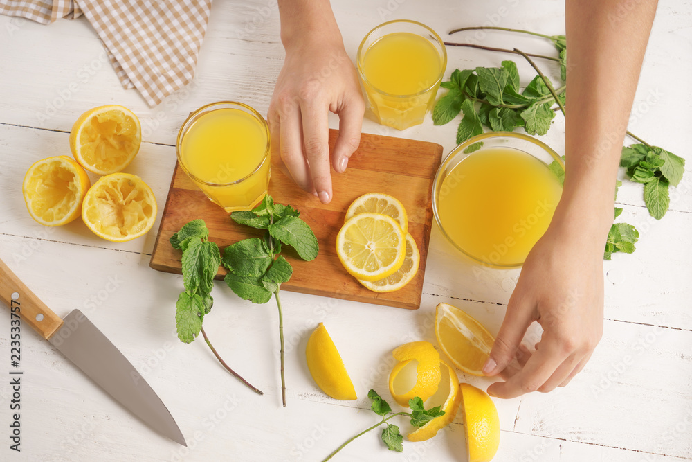 Woman preparing fresh lemon juice on light table