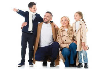  stylish happy family hugging with children in beige coats, boy showing something isolated on white