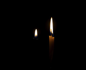 Candle burning brightly close up on the black background