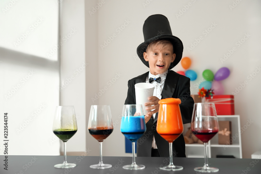 Cute little magician showing trick indoors