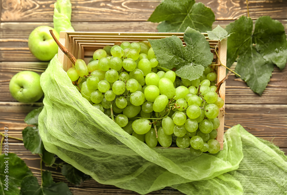 Box with sweet grapes on wooden table