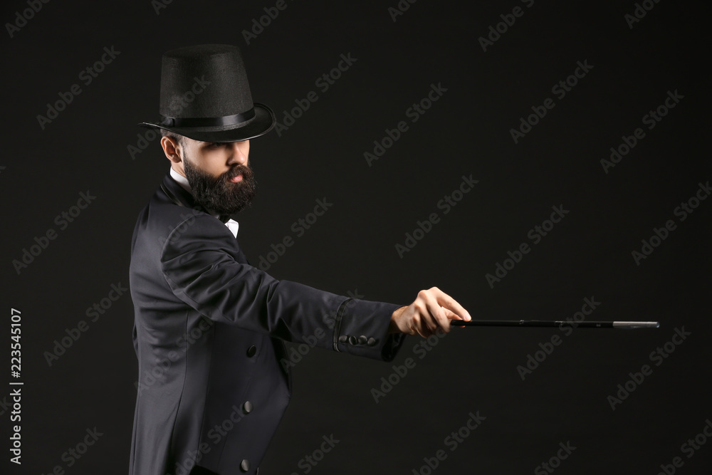 Male magician showing tricks on dark background