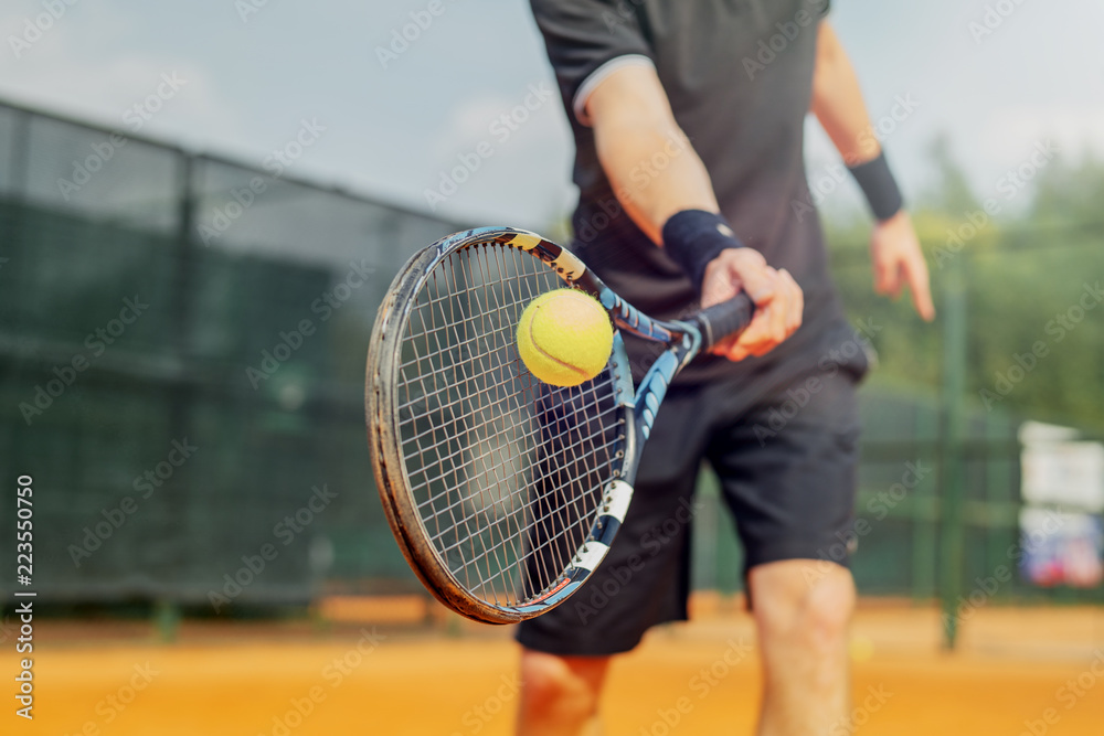 Close up of man playing tennis and beating the ball with a racket. - obrazy, fototapety, plakaty 