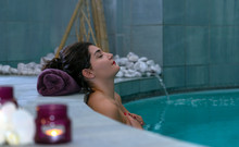 Beautiful Woman Relaxing In Pool Jacuzzi  In Spa Salon. Happy Young Beautiful Girl Enjoying Massage At The Beauty Salon Spa. Concept Of Wellness, Bodycare, Healthy Lifestyle