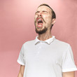 Young funny handsome man with beard and mustache sneezing with spray and small drops, studio portrait on pink background. Comic, caricature, humor. illness, infection, ache. Health concept