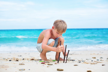 boy playing with natural sticks. blue sea white sand