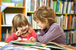© ulza - Cute two little kids, brother and sister  reading a book together in library