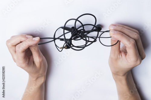 Fotografie, Obraz Female hands unravel the black little headphones on a white background