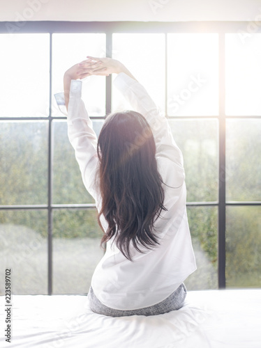 Fotografie, Obraz Beautiful young woman waking up in the morning in the white shirt and stretching