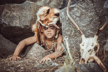 Caveman, Manly Boy Hunting Outdoors. Prehistoric Tribal Boy Outdoors On Nature. Young Shaggy And Dirty Savage, Warrior And Hunter Hiding In An Ambush Behind A Stone In Cave. Primitive Ice Age Man In