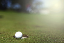 Close-up Of Golf Ball By Hole During Sunny Day