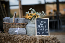 Sheets In Wicker Basket With Flowers And Blackboard At Wedding Ceremony