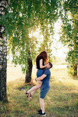 young loving couple in nature in summer on a background of green leaves