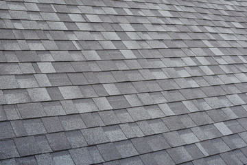 Grey asphalt roof shingles textured surface as abstract background.