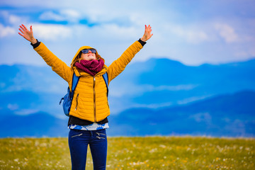 Wall Mural - Girl with rucksack on the top of hilly landscape.