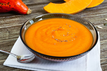 Wall Mural - Delicate pumpkin puree in a black glass bowl on a wooden table.