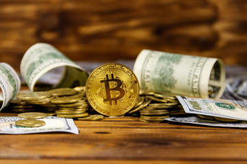 Golden bitcoin and dollars on wooden background