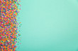 Colorful sprinkles on edge of green background