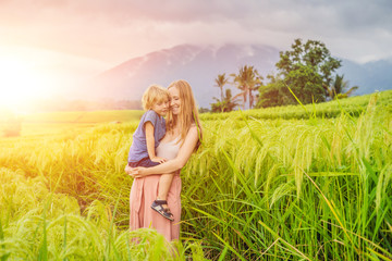 Mom and son travelers on Beautiful Jatiluwih Rice Terraces against the background of famous volcanoes in Bali, Indonesia Traveling with children concept with sunlight