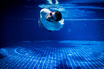 young man with sunglasses enjoying the swimming pool abstract summer fun underwater swimming jump diving background