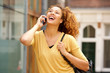 © mimagephotos - young woman talking on mobile phone and laughing in the city