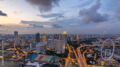 Fototapeta na szkło Skyline of Singapore with famous Singapore Ferries Wheel day to night timelapse at twilight