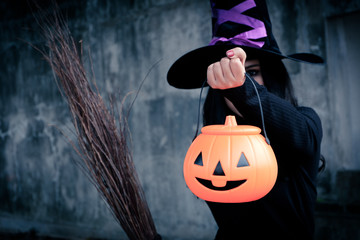 Young woman in witch Halloween costume hold a orange pumpkin