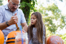 A Father Carving A Jack-o-lantern With His Daughter. 