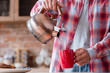 © golubovy - traditional quick breakfast of tea and pastry. food and eating habits concept. man pouring boiling water from kettle to in a red mug.