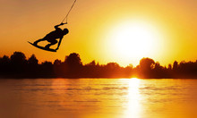 Wake Board A Man Does A Trick At Sunset On The Board On The Water Splashes