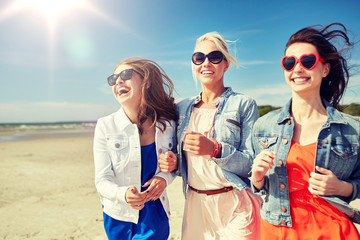 Wall Mural - summer vacation, holidays, travel and people concept - group of smiling young women in sunglasses and casual clothes running along beach