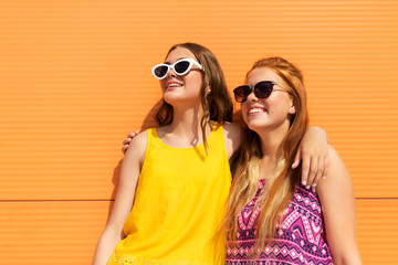 fashion, leisure and people concept - smiling teenage girls in summer clothes hugging outdoors